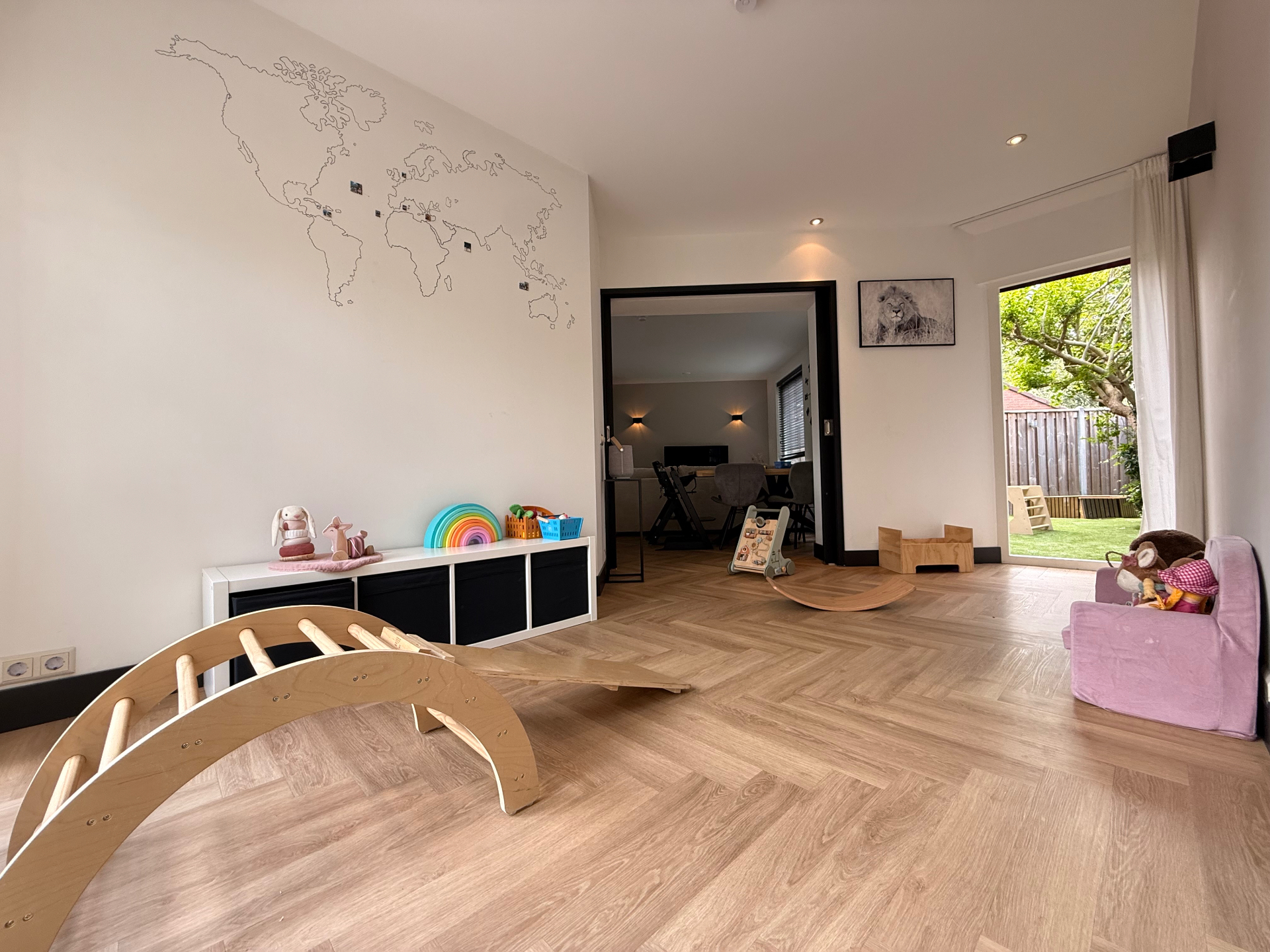 Ruime speelkamer met visgraat PVC-vloer, speelgoed en klimboog