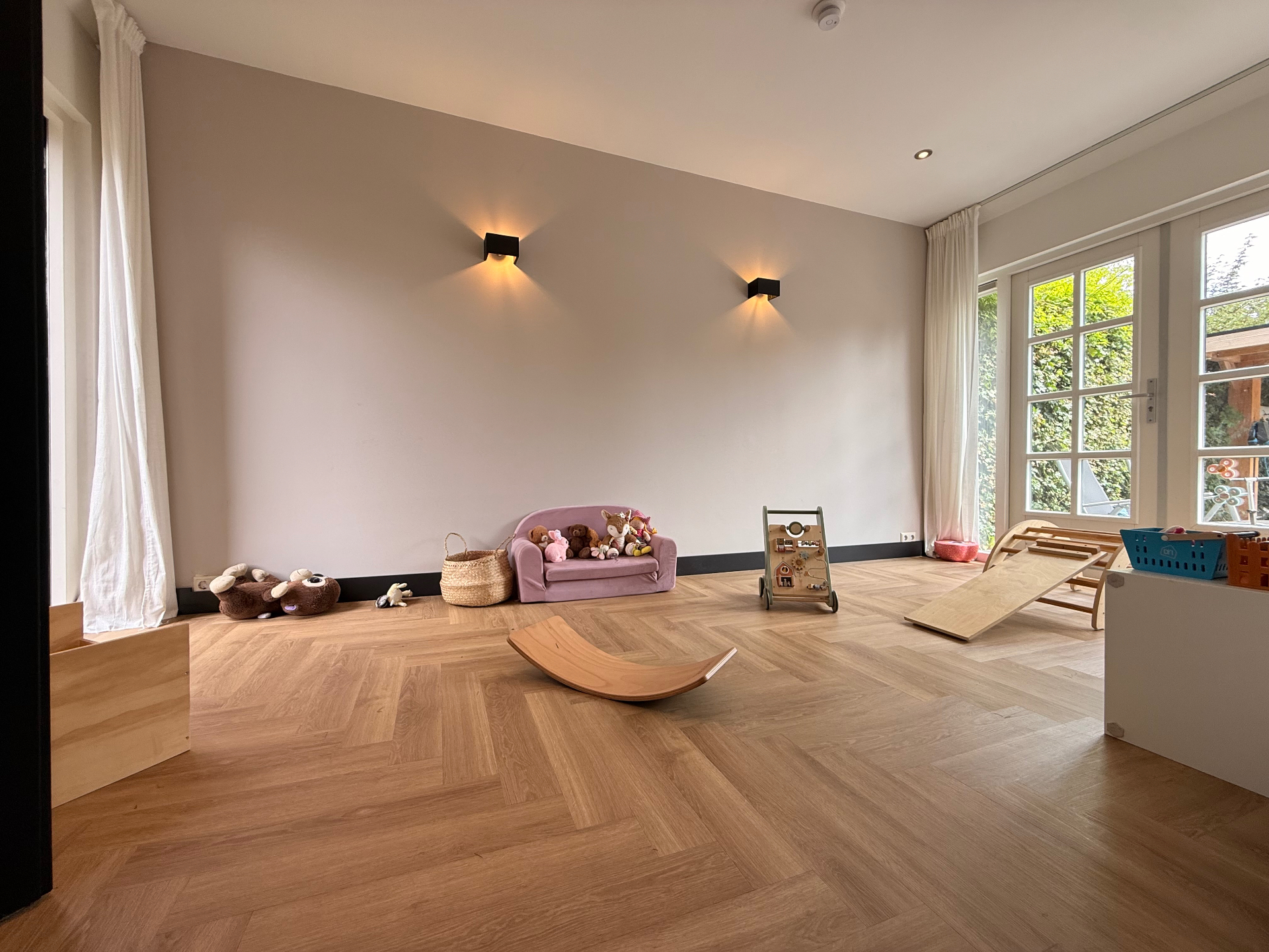 Aparte speelkamer met veel licht, zachte kleuren en houten speelgoed